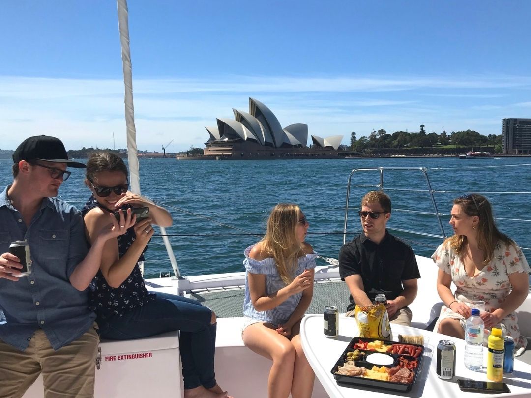 Corporate boat cruise on Rockfish catamaran people chatting with Sydney Opera House in background